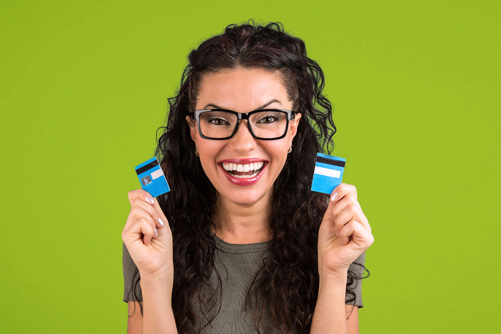 Woman wearing glasses holding half of a credit card in each hand because she doesn't need credit cards anymore